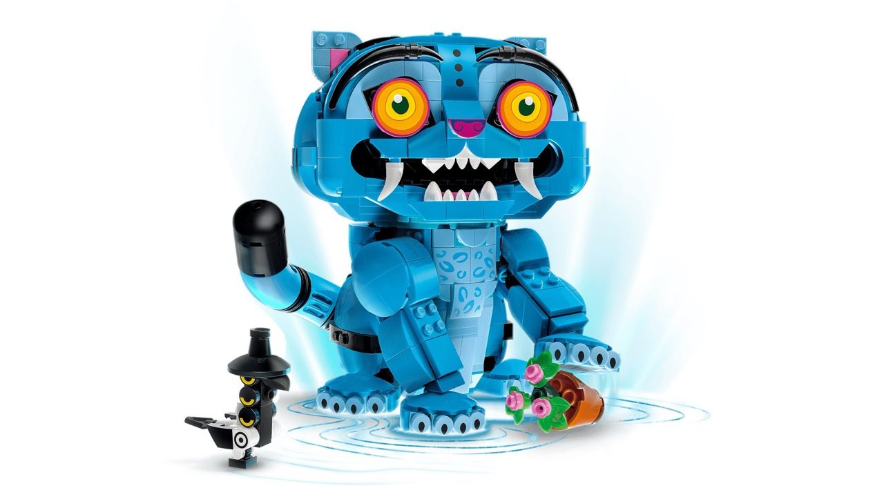 Blue LEGO buildable monster with glowing orange eyes, sharp teeth, and articulated limbs, displayed with small black minif…