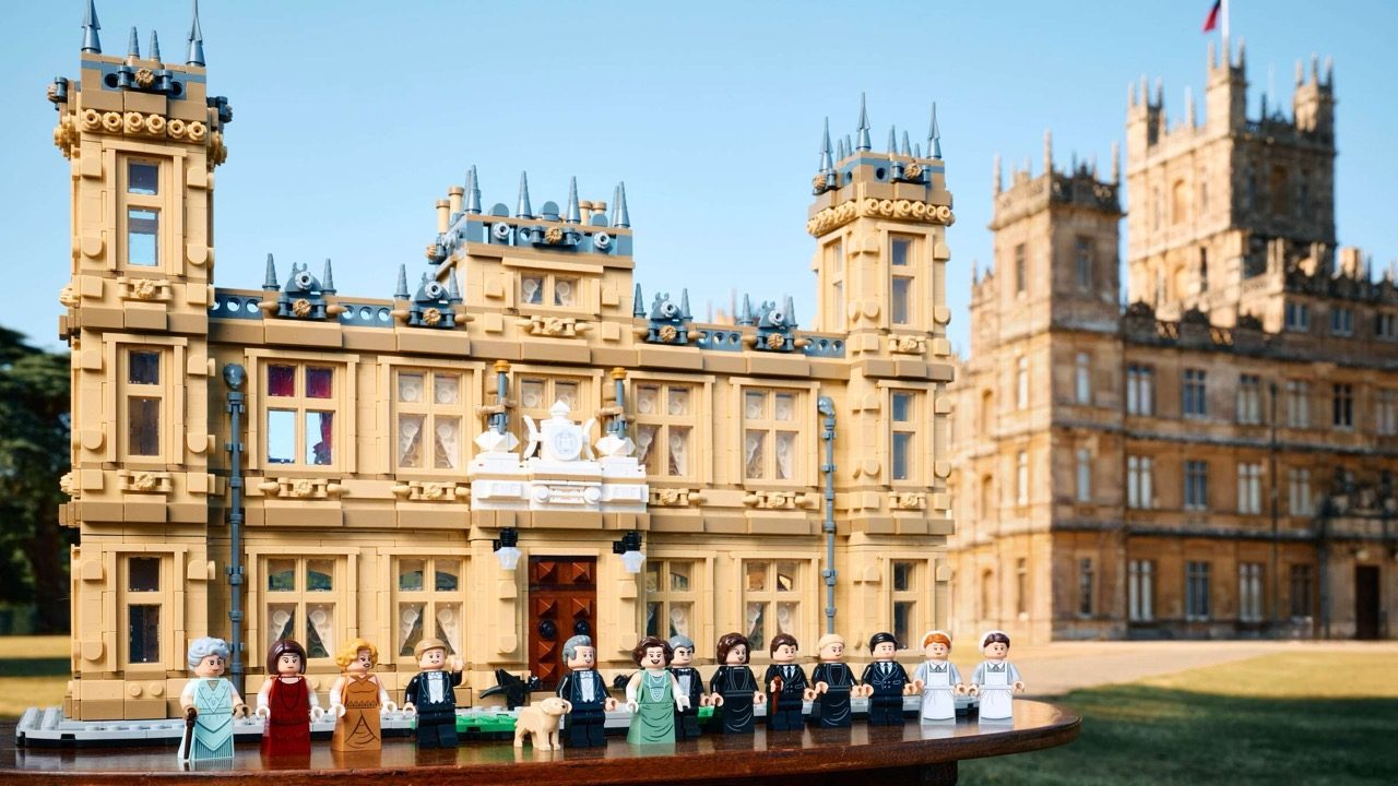 LEGO Downton Abbey set displaying Highclere Castle with minifigures lined up in front of the detailed brick structure.