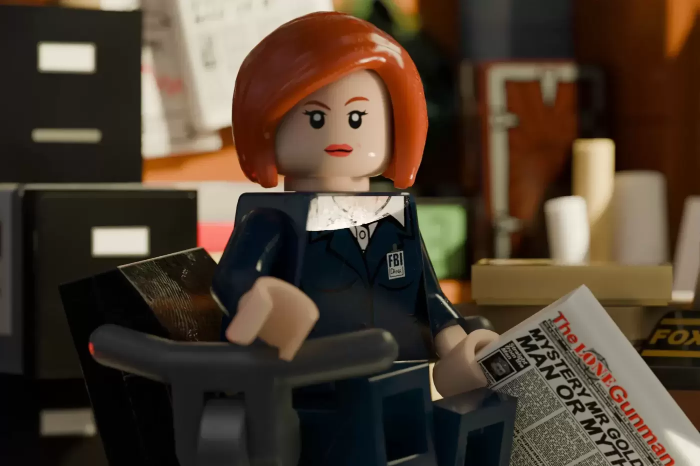 LEGO minifigure with orange hair in FBI outfit holding newspaper, sitting at desk in office setting.