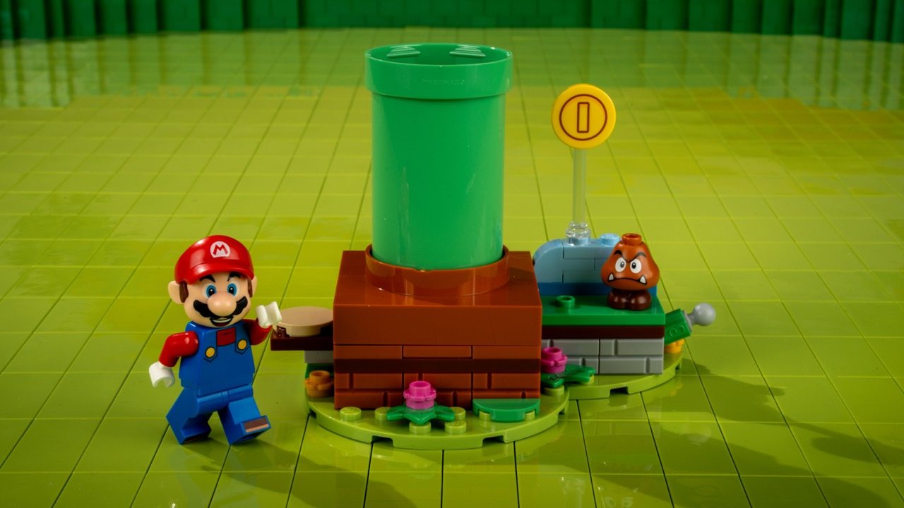 LEGO Super Mario set featuring Mario minifigure, green pipe, Goomba enemy, and coin marker on lime baseplate.