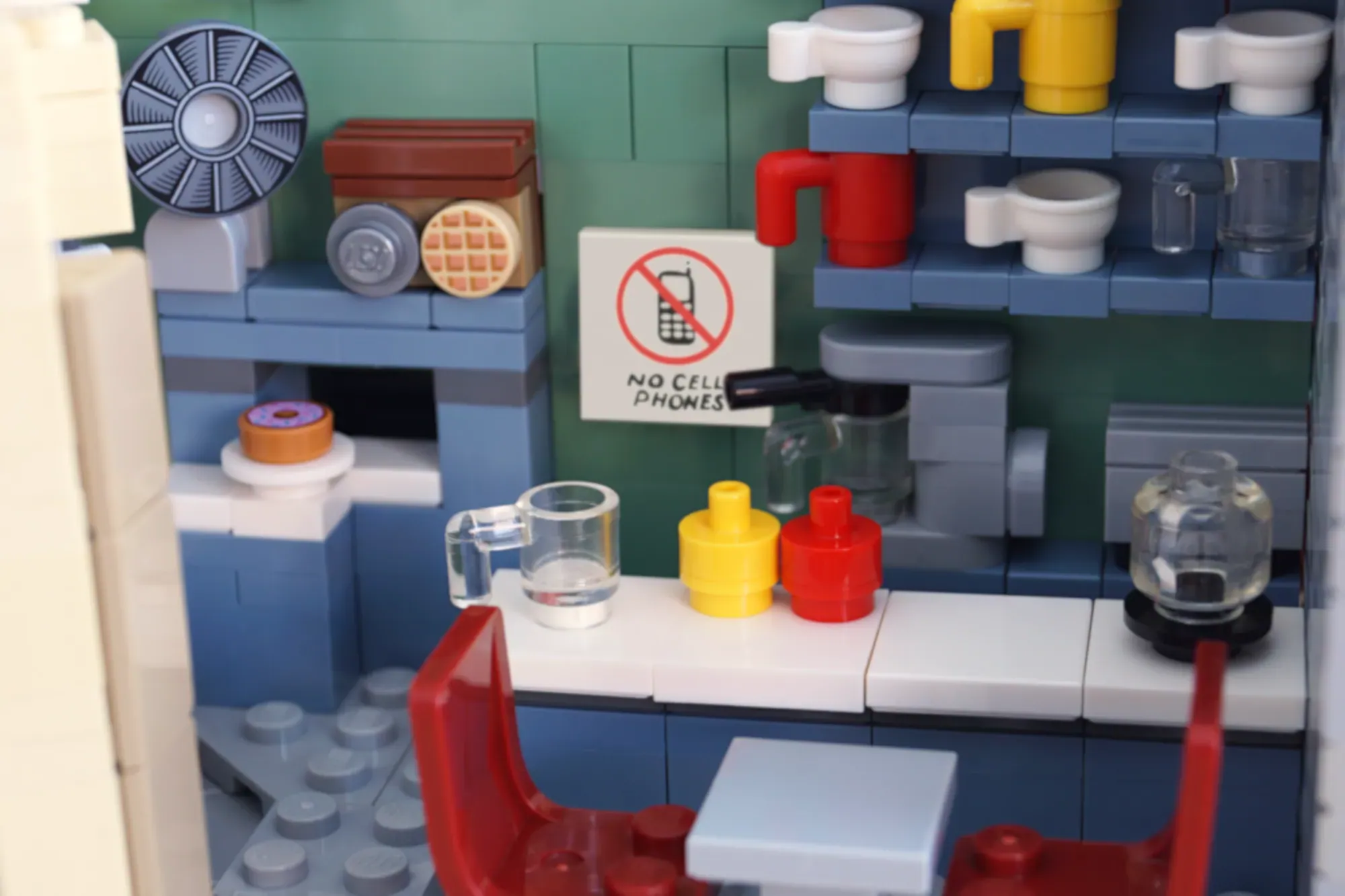 LEGO Luke's Diner interior with kitchen counter, appliances, "No Cell Phones" sign, and minifigure accessories.