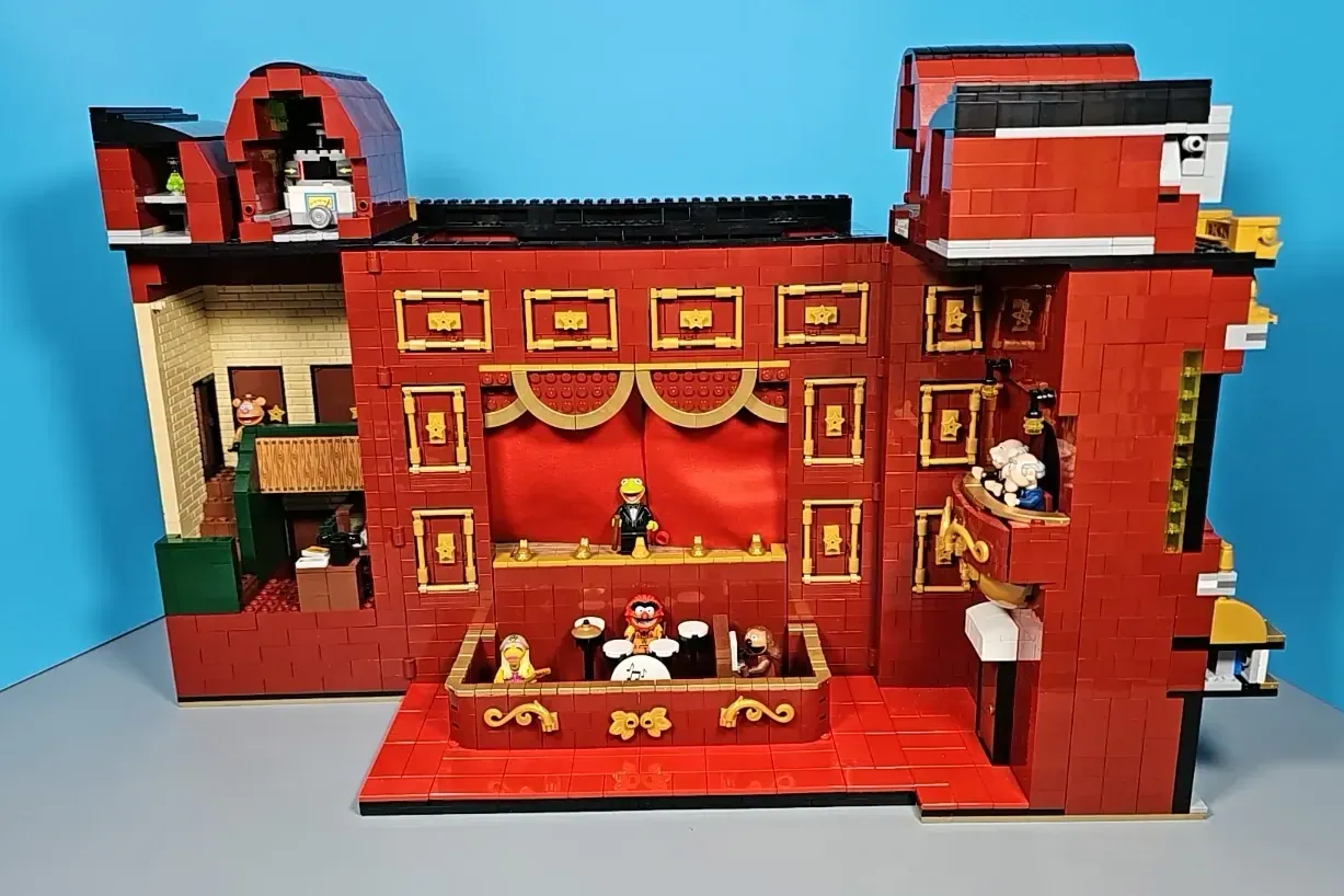LEGO Muppet Theatre set with red brick facade, stage, balconies, and minifigures displayed against blue background.
