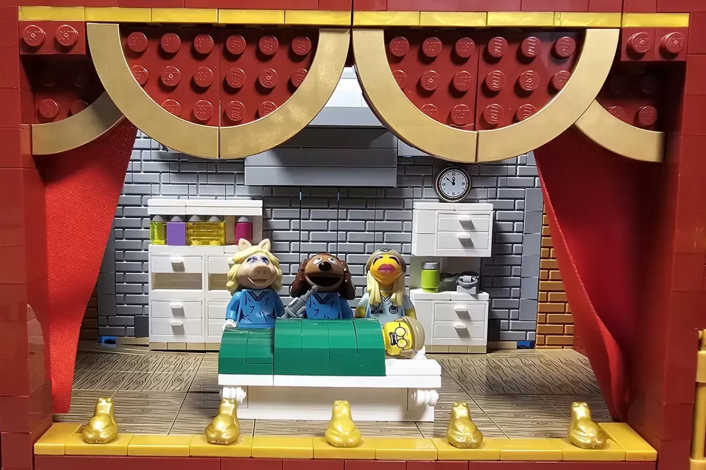 LEGO Muppet Theatre set featuring Miss Piggy, Fozzie Bear, and Janice minifigures at a green desk on stage.
