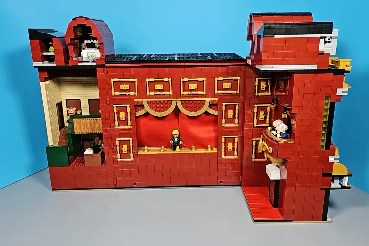 LEGO Muppet Theatre set with red brick facade, gold-trimmed stage doors, minifigures, and detailed interior rooms against …