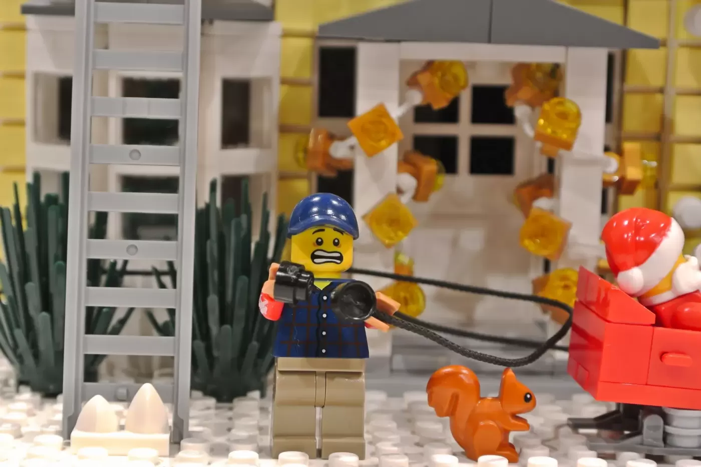 LEGO minifigure with camera documents chaotic Christmas display with falling decorations and squirrel.