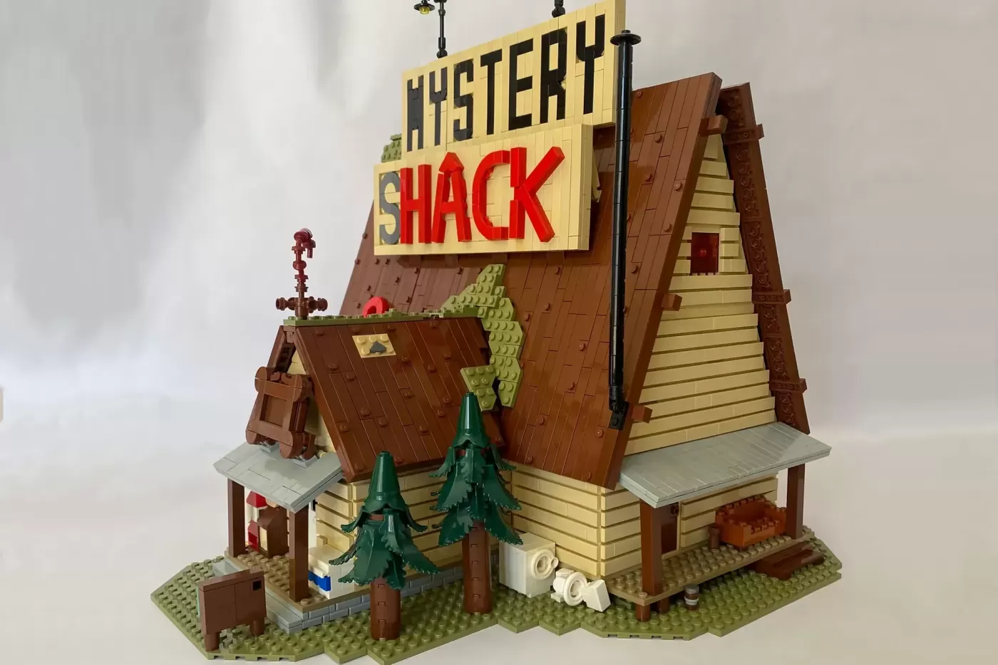 LEGO Gravity Falls Mystery Shack MOC with yellow signage, brown wooden structure, green trees, and detailed architectural …