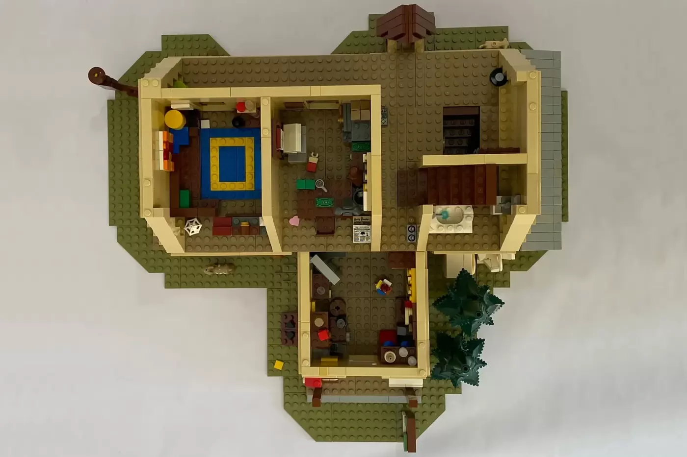 LEGO Mystery Shack MOC with multiple rooms, minifigures, furniture, and outdoor elements on green baseplate.
