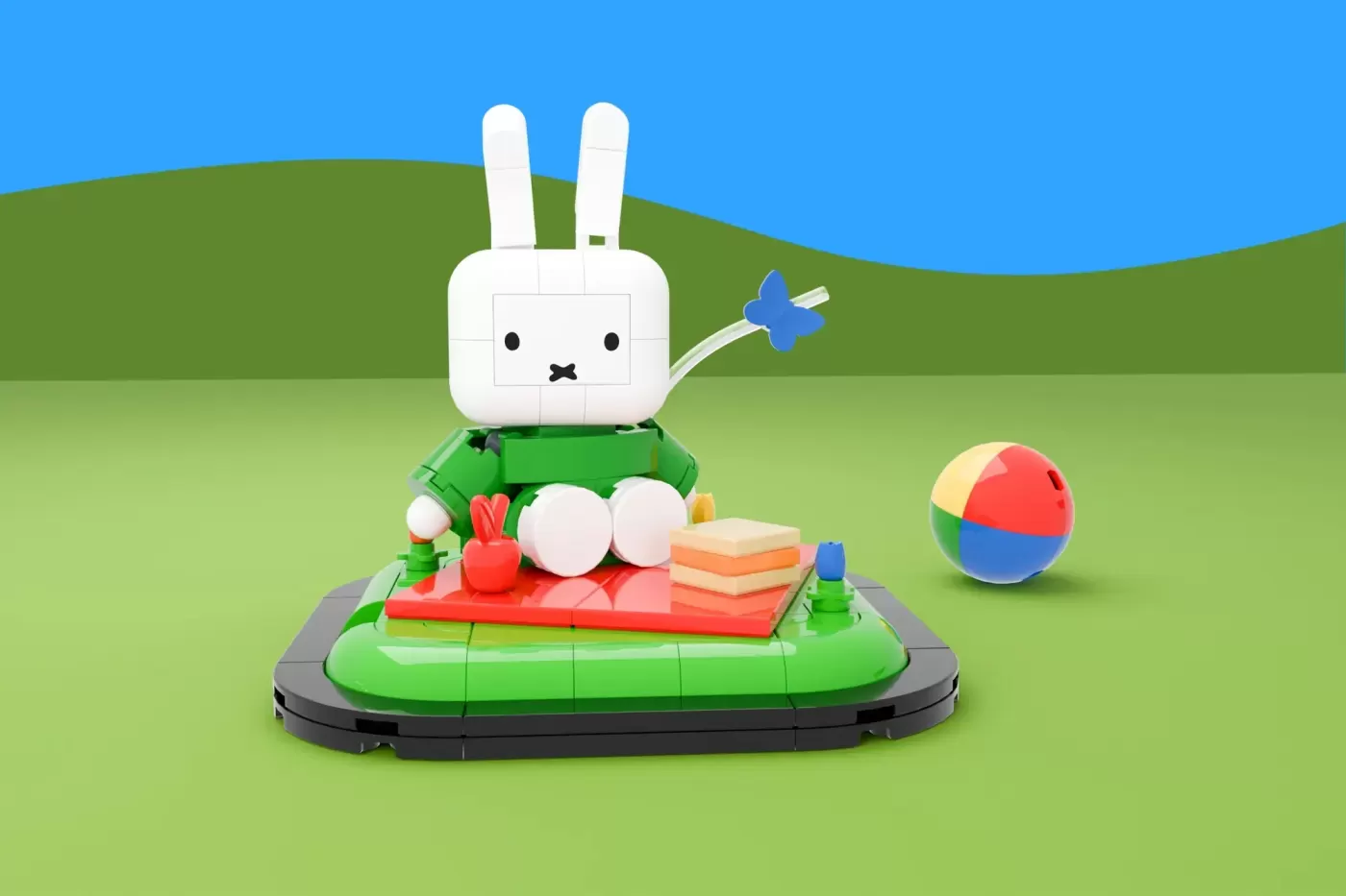LEGO Miffy bunny figure sitting on green base with books, flowers, and colorful beach ball nearby.