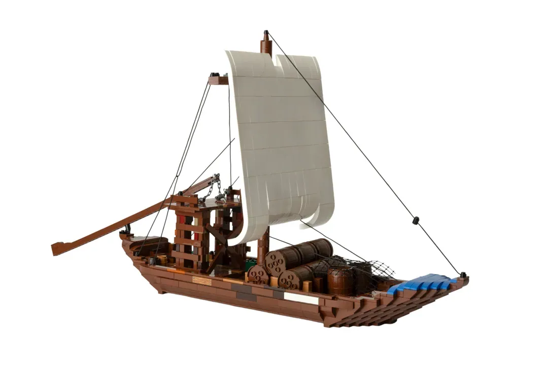 LEGO Barco Rabelo model with tan sail, brown wooden hull, cargo barrels, and blue accents on deck.