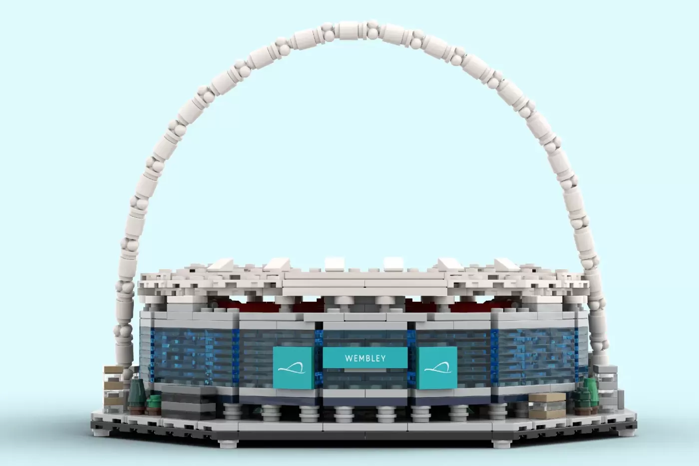 LEGO model of Wembley Stadium featuring its iconic white arch and turquoise signage on light blue background.