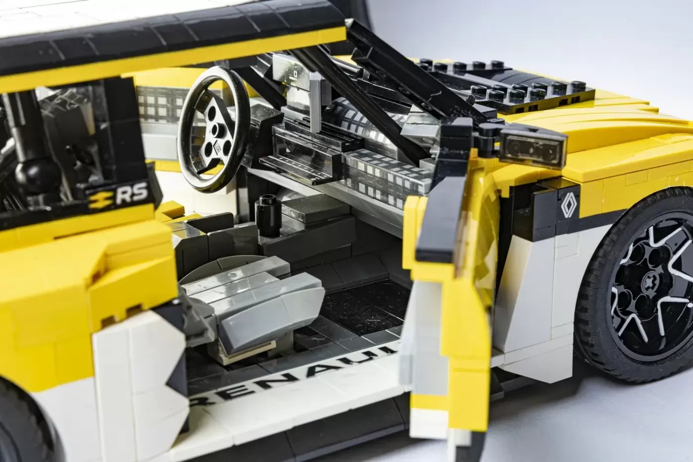 LEGO Renault 5 Turbo 3E with open hood and door, showing detailed yellow and white interior and engine components.