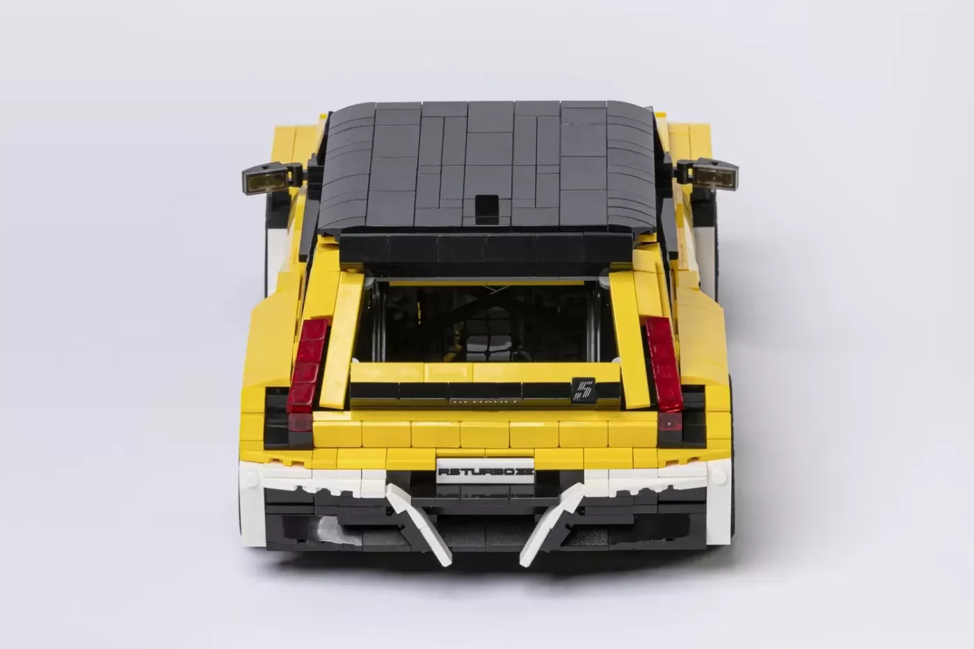 LEGO Renault 5 Turbo 3E model viewed from above, showing yellow body with gray roof and white bumper details.