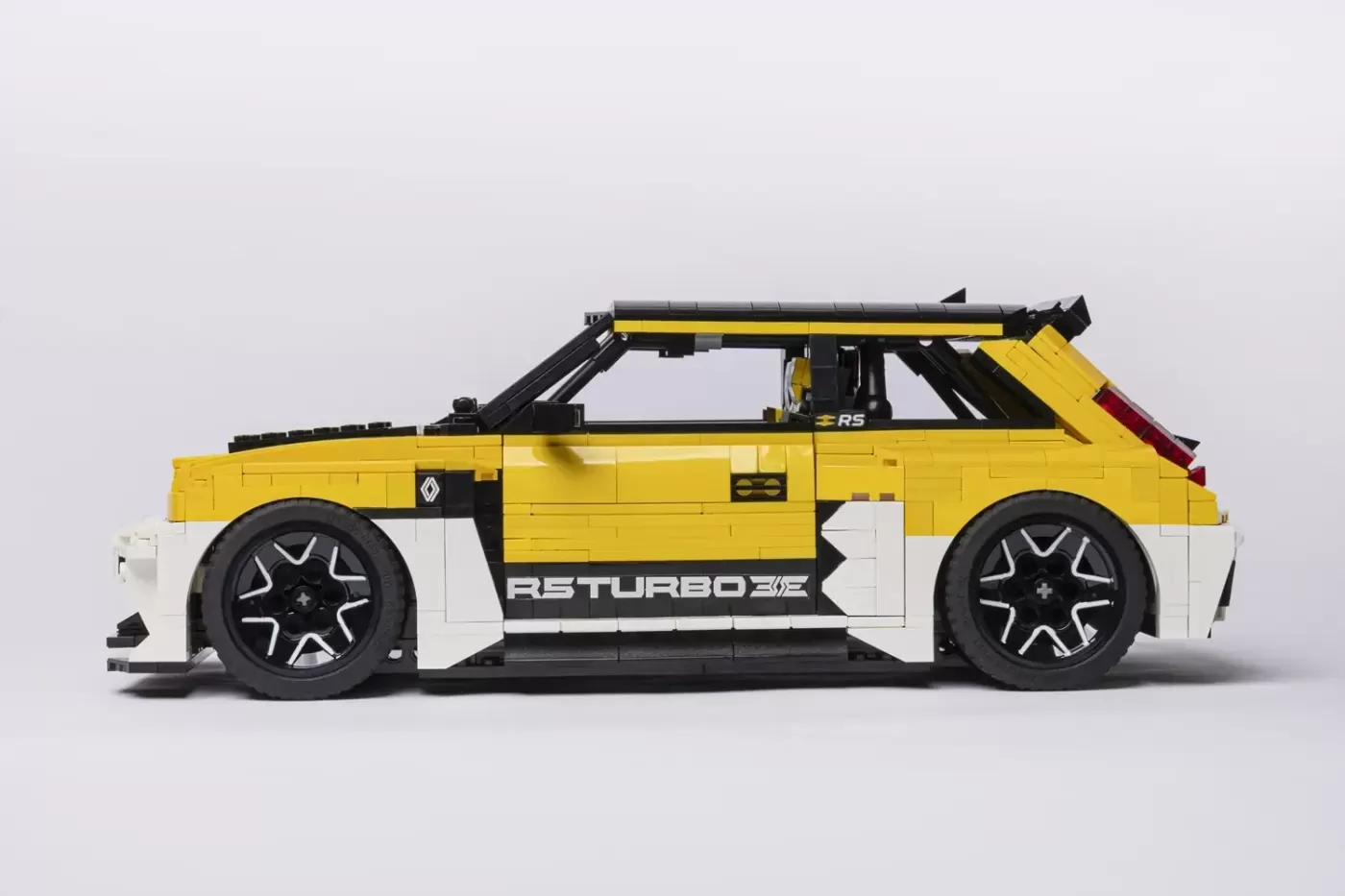 LEGO Renault 5 Turbo 3E model in yellow and white, displayed in profile view with opening door and detailed wheels.