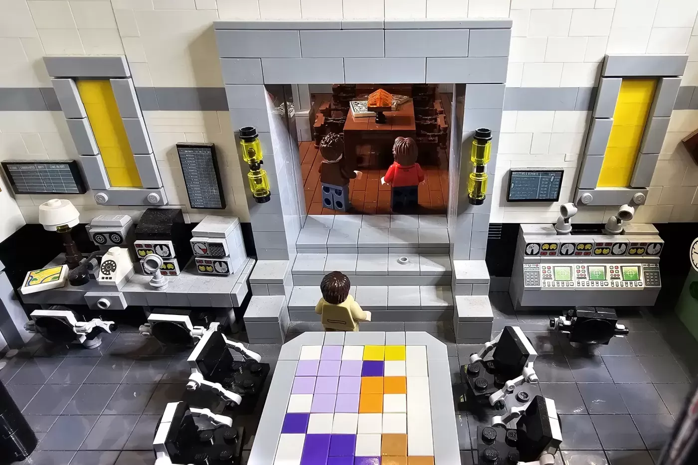 LEGO bunker set featuring control room with monitors, elevator shafts, and figures in central chamber with orange flooring.