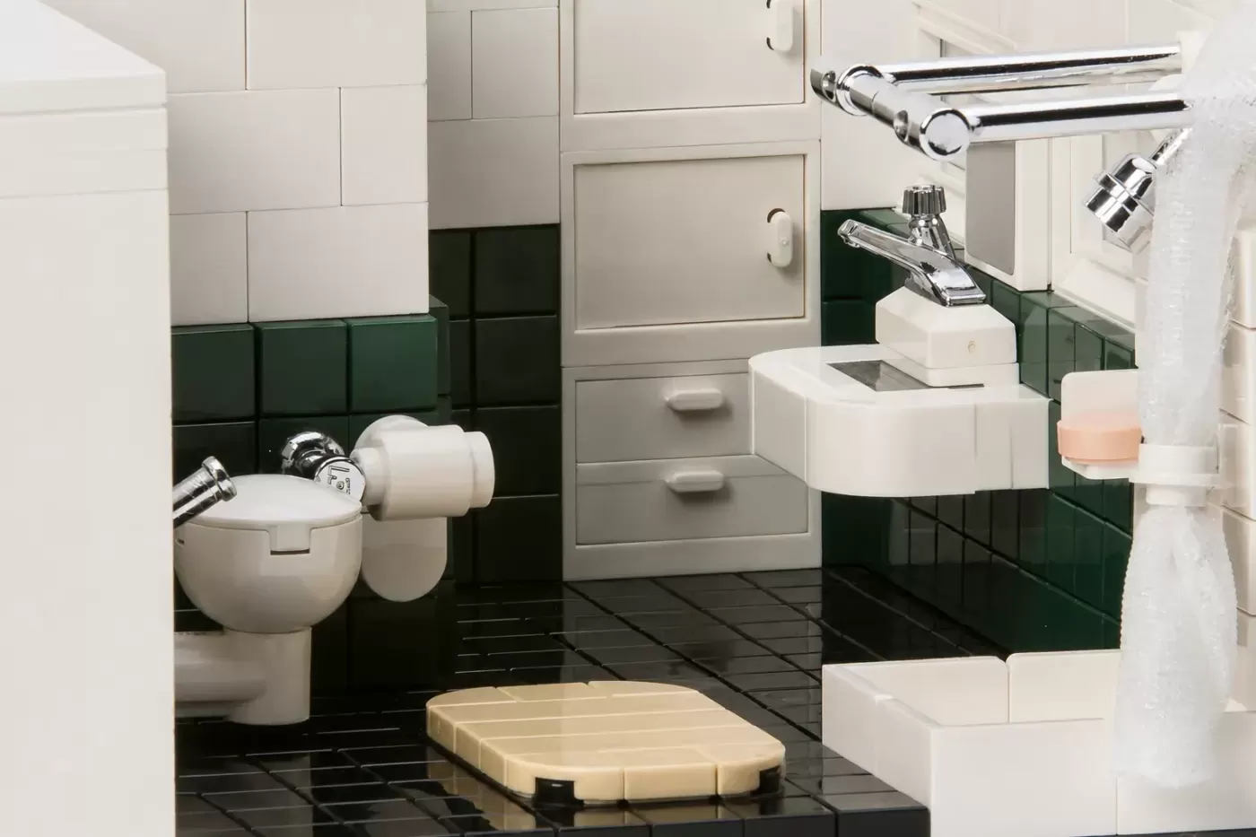 LEGO bathroom set with white and green tile walls, black floor, sink, toilet, and chrome fixtures.