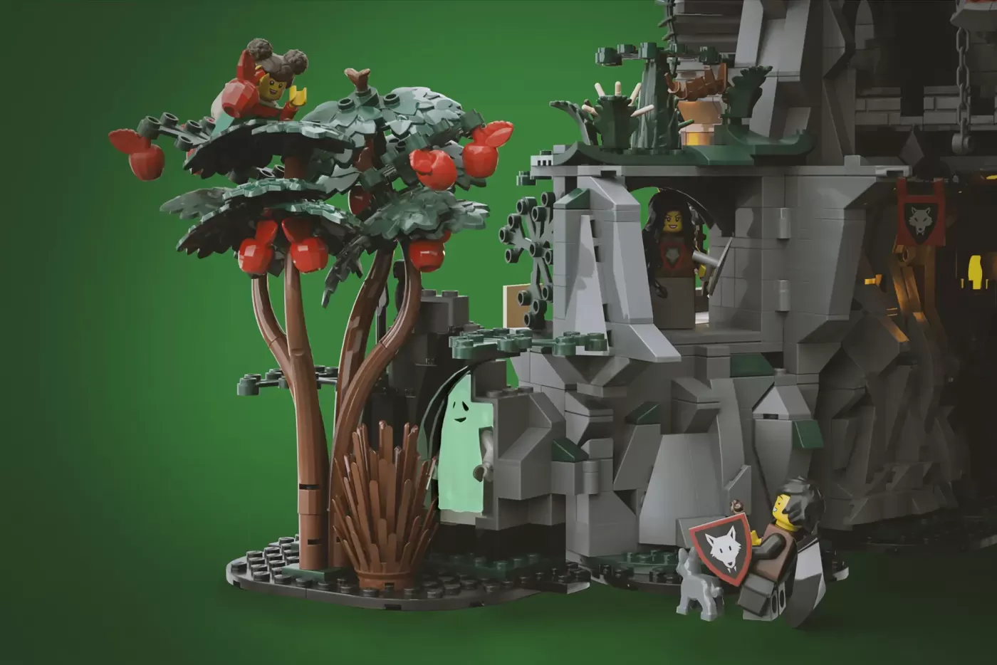 LEGO Wolfpack Fanghold castle with stone wolf sculpture, apple tree, minifigures, and detailed gray stone architecture.